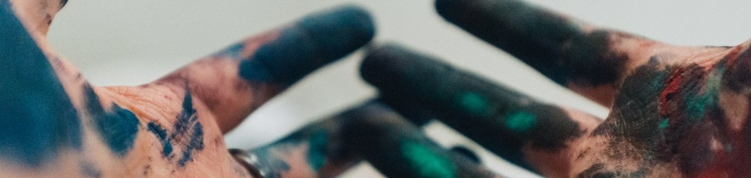 Två uppvända händer täckta av färg mot ljus, suddig bakgrund